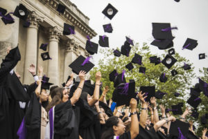 Students on graduation day at Portsmouth university, throwing their mortarboard hats into the air