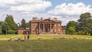 Berrington Hall is a large country house set in grassy parkland with large trees and sheep.