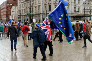 People at a Brexit demonstration. A protester carries a European Union flag and a British flag