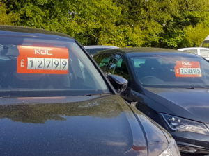 Row of cars for sale with prices shown in the windscreen