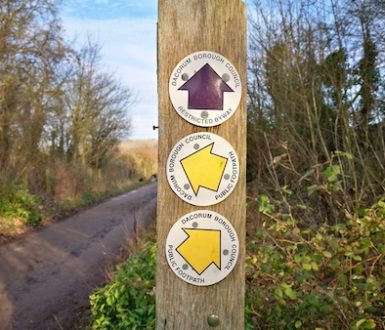 Wooden pole showing yellow arrows for public footpaths