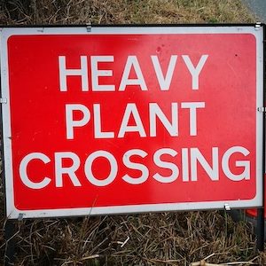 Red sign with the words Heavy Plant Crossing