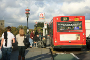 Bus at a bus stop, man in wheelchair is using the ramp access