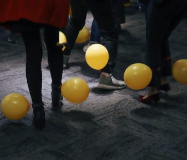 the legs of people dancing, with yellow balloons floating about