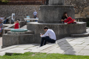 People sitting outside on a sunny day, one man looking at his mobile phone