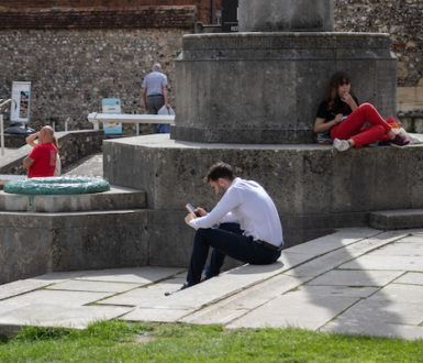 People sitting outside on a sunny day, one man looking at his mobile phone