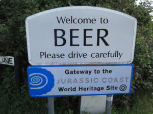 A road sign saying Welcome to Beer please drive carefully. Beer is a town in Devon.