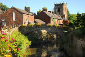 View of a charming village with church in the background and a bridge in the foreground