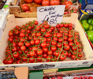 A box of cherry tomatoes on a market stall, priced by the half pound