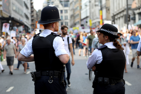2 police officers viewed from behind in front of a crowd of people