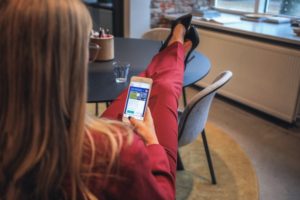 Woman in suit with her feet on the table in front of her. She is holding a mobile phone