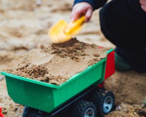 Child putting sand in toy truck