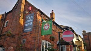 Side of pub building showing a colorful sign hanging from the wall and the words 'free house'