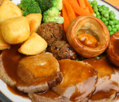A British roast dinner, consisting of roasted meat, roast potatoes, boiled carrots, peas and broccoli plus a Yorkshire pudding and stuffing balls