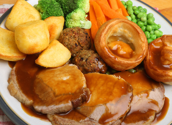 A British roast dinner, consisting of roasted meat, roast potatoes, boiled carrots, peas and broccoli plus a Yorkshire pudding and stuffing balls