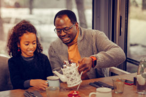Man pouring tea for his daughter